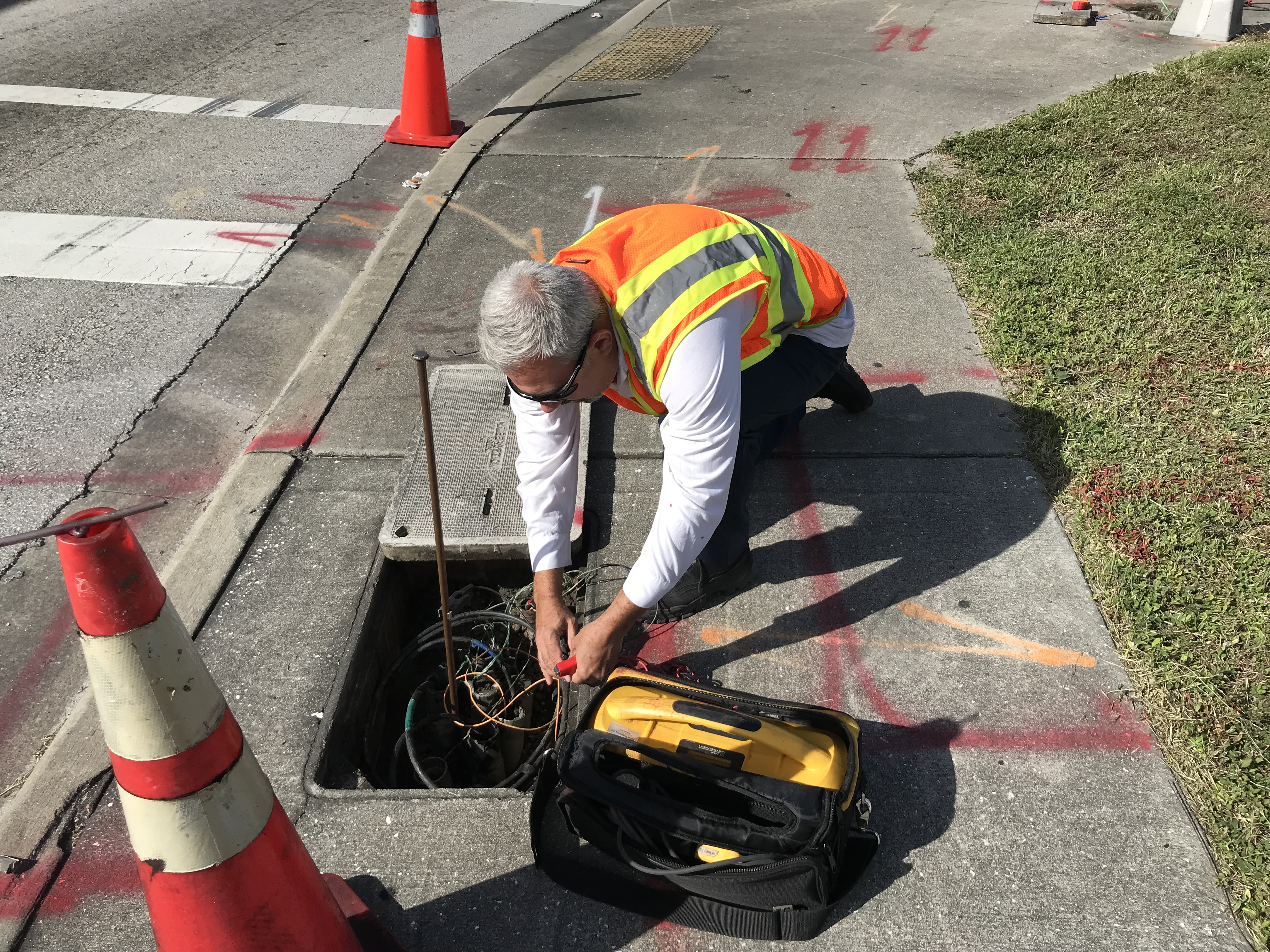 Worker pulling wires from box in sidewalk