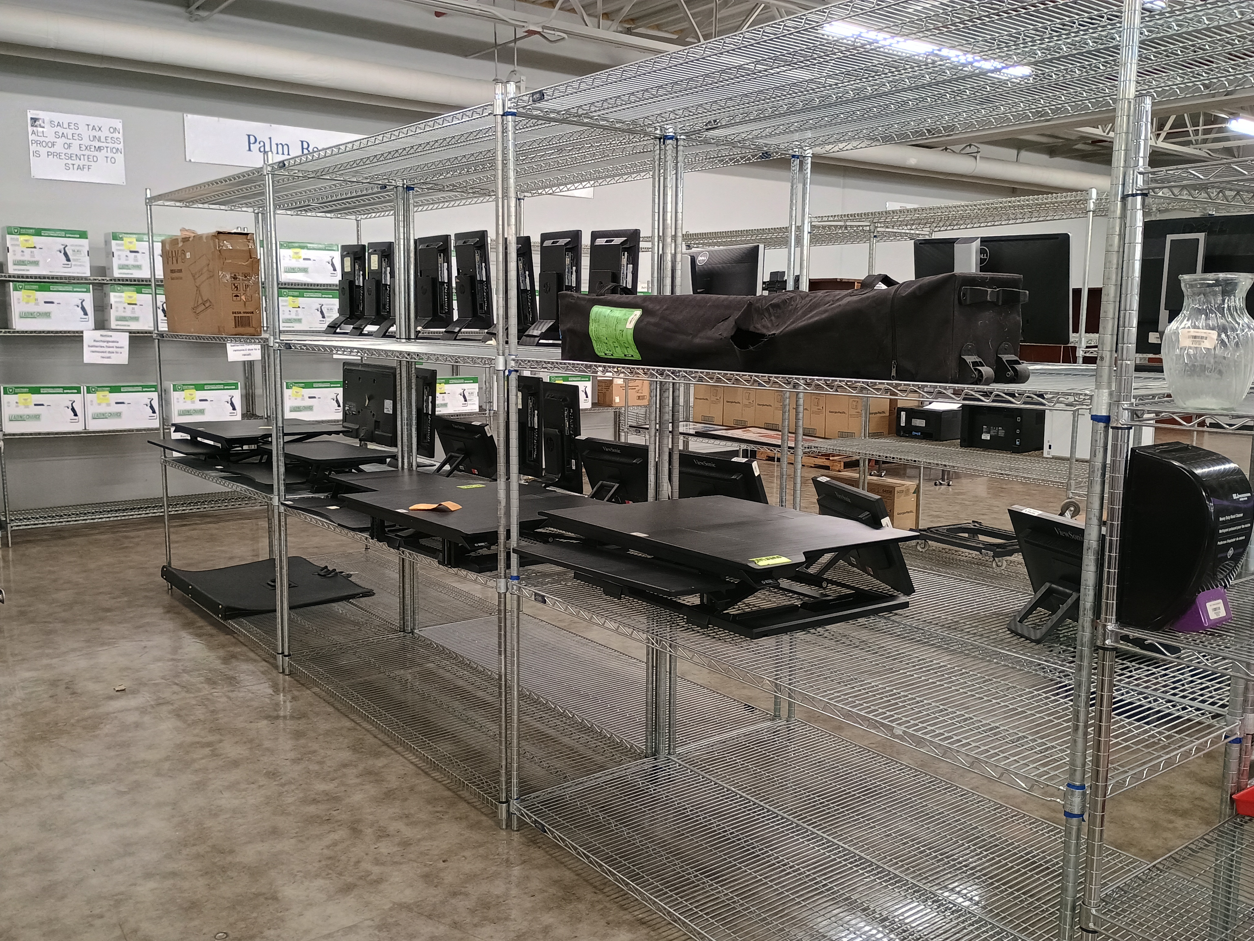 Metal wire racks with various merchandise, canopy frame in bag and sit to stand desk riser.jpg