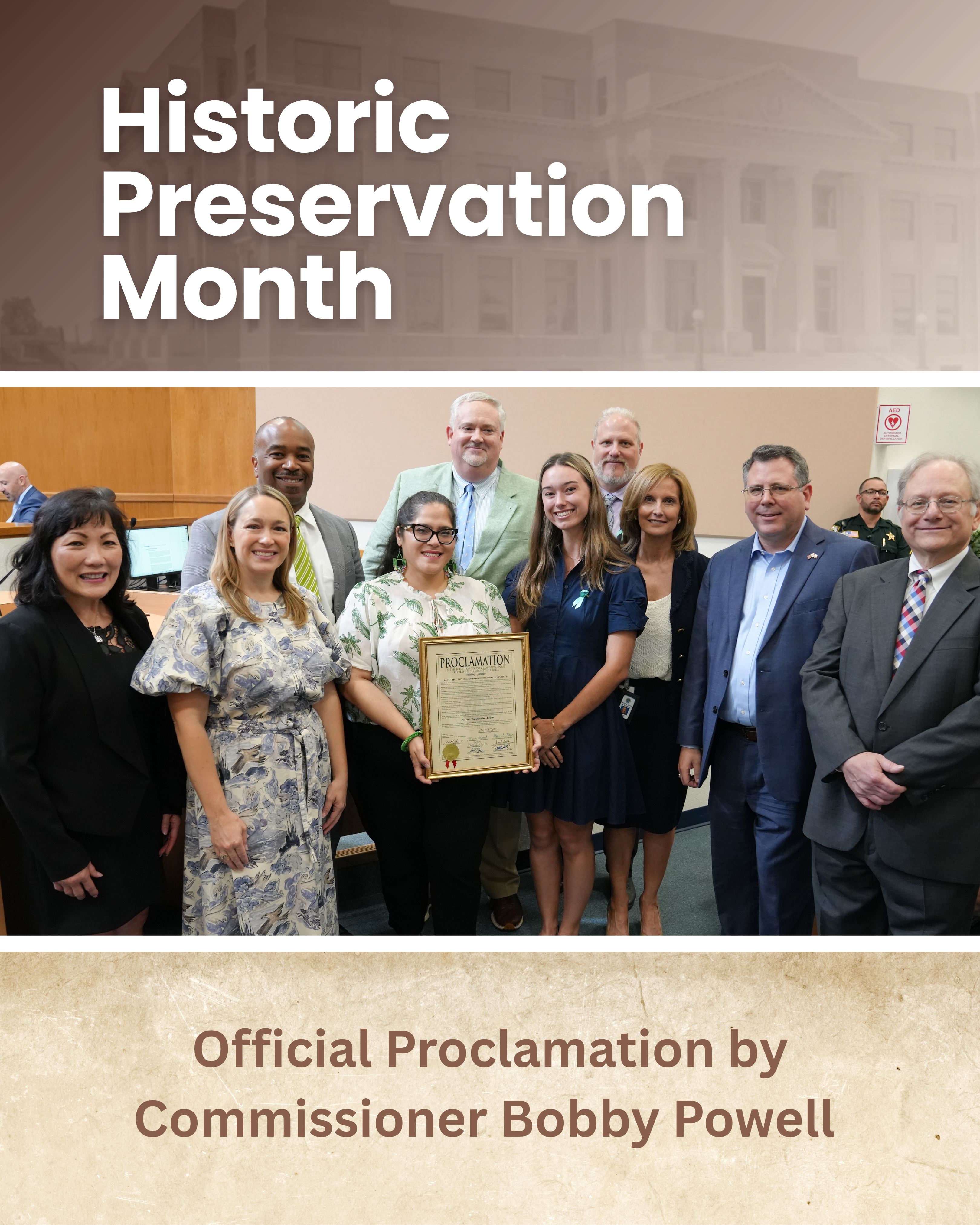 A group of officials and community members gather for a photo to celebrate Historic Preservation Month, holding an official proclamation issued by Commissioner Bobby Powell.